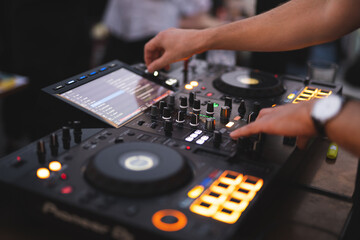 Obraz premium a DJ plays music on a controller at a party