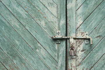 old metal lock on a wooden door with cracked paint