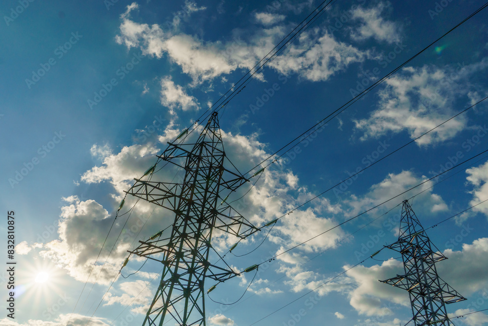 Wall mural Power lines and high-voltage wires against a background of blue sky and fluffy clouds. Energy infrastructure of Ukraine.