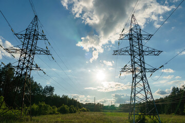 Power lines and high-voltage wires against a background of blue sky and fluffy clouds. Energy...