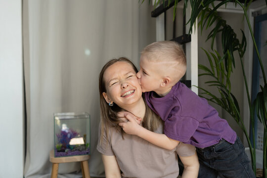 Boy kissing mother by the fish tank at home