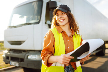 Portrait of a female trucker standing in front of truck and looking at camera.Transportation...