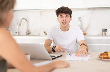 Guy manager tells woman client about specifics of design of microloan, about benefits and advantages. Seller draws up contract on laptop