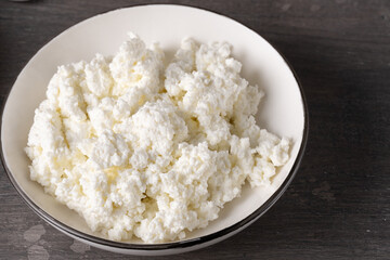 Bowl of cottage cheese isolated on grey background, top view