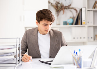 Obraz premium Man office manager sitting at table and using laptop computer
