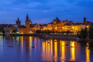 Evening view of prague's illuminated architecture reflected on the vltava river