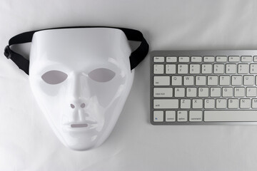 白い仮面とキーボード。ハッキングのイメージ