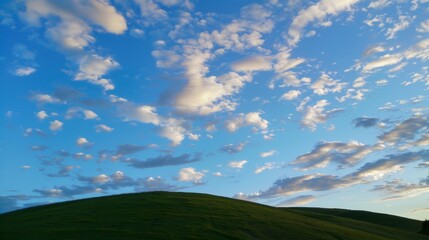 Fototapeta premium an unedited photograph of a green hill and blue sky with white clouds in the Los Carneros American Viticultural Area of Wine Country, California. At night, shadows, sunset, dusk. 