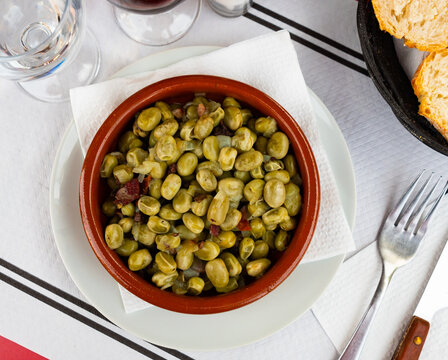 Delicious habas con jamon served on plate in cafe. Spanish dish