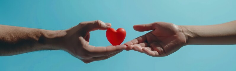 Fototapeta premium Female hand passes red heart to male hand against blue background closeup. Kindness and charity concept