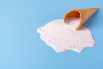 Pink ice cream melting and spilling from the waffle cone.