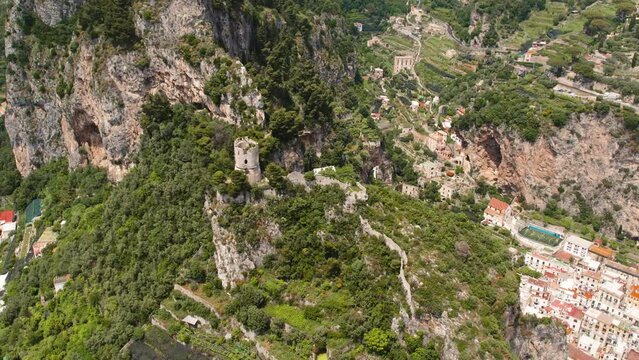 Aerial view of terraced greenery and historic tower Torre dello Ziro in the mountainous backdrop of Atrani town, Amalfi coast, Italy.