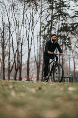 Fototapeta premium Focused male cyclist on a mountain bike contemplating nature, riding along a scenic path in a park with autumn foliage.