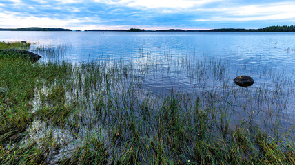 A picturesque setting with water, lush vegetation, rocks, and sky