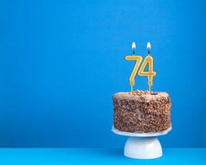 Birthday celebration with candle 74 - Chocolate cake on blue background