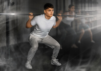 Young man in sportswear training with barbell in gym