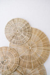 Panel of round woven seaweed rugs hangs on a white wall