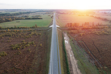 Railway and asphalt road through autumn forest. Aerial view