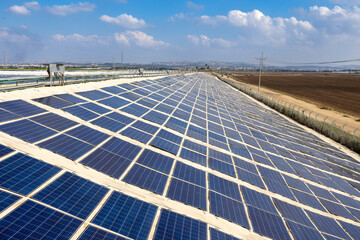 Row of solar panels. In the background sky and fields