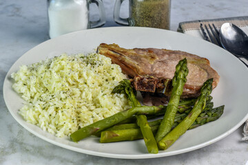 pork chop  with a side of rice and asparagus