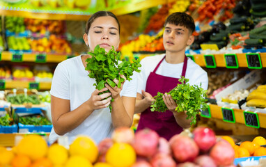 Friendly guy seller helps a girl buyer who came to the store for shopping, choose a fresh greenery