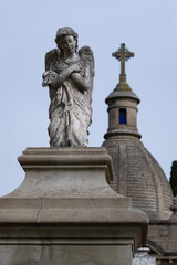 Escultura de un ángel arrodillado con una capilla de fondo