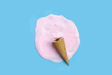 Melting ice cream ball with waffle cone on blue background.