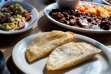 Tacos on a separate plate with two other plates of Mexican food next to it