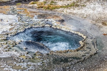Hot spring in rocky surroundings under sunny skies