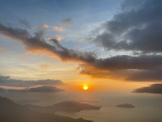 Sunset over the ocean and mountains with rolling clouds at dusk