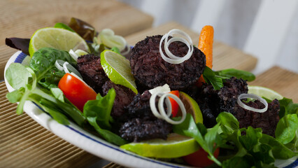 Delicious Catalan blood sausage with rice with garnish of greens, vegetables and lemon slices