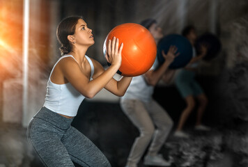 Young athletic woman in sportswear training with ball in gym