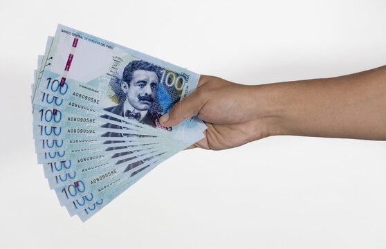 male hand holding fan of banknotes on white background peruvian sol - peruvian salary