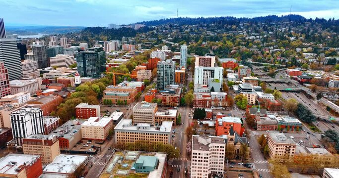 Flying over the plain urban part of Portland approaching the mountainous one. Modern American city panorama from top.