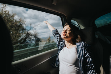 Carefree young woman with her arm outstretched, enjoying the sunlight and freedom during a scenic car ride.