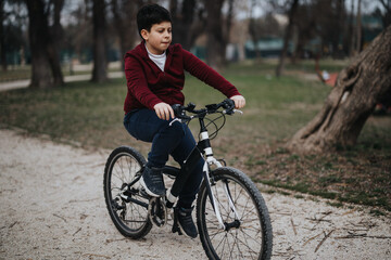 An active young kid enjoys a sunny day outdoors cycling in a green park.