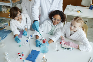 High angle view of unrecognizable teacher and multi-ethnic kids doing experiments in Chemistry class
