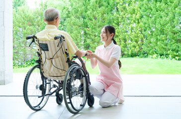 車椅子に乗った高齢者の介護をするヘルパー