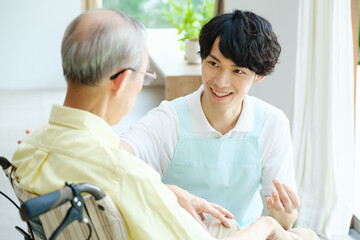 Obraz premium 車椅子に乗った高齢者と会話をする介護福祉士