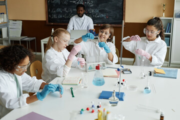 Multi-ethnic group of kids doing lab experiment in classroom during Chemistry lesson at school, high angle view shot