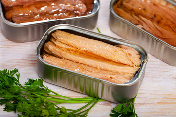 Opened cans of preserved mackerel fish fillets on wooden background