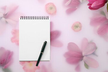 Guest list. Notebook, pen and magnolia on spring floral background, flat lay. Space for text
