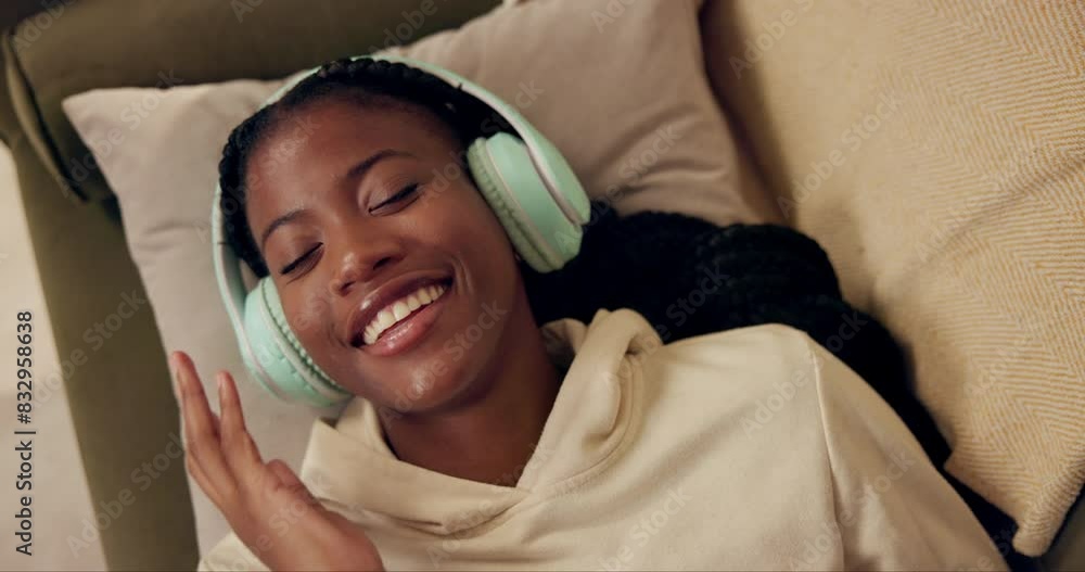 Wall mural African woman, headphones and above on sofa with smile, relax and singing with music in home living room. Girl, listening and happy for streaming, audio subscription or lying on lounge couch in house