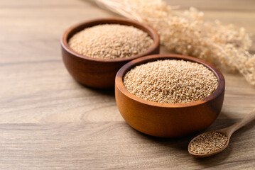Brown quinoa seed in bowl with spoon on wooden background, Healthy food ingredient