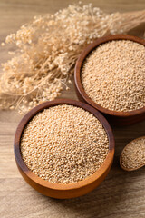 Brown quinoa seed in bowl with spoon on wooden background, Healthy food ingredient