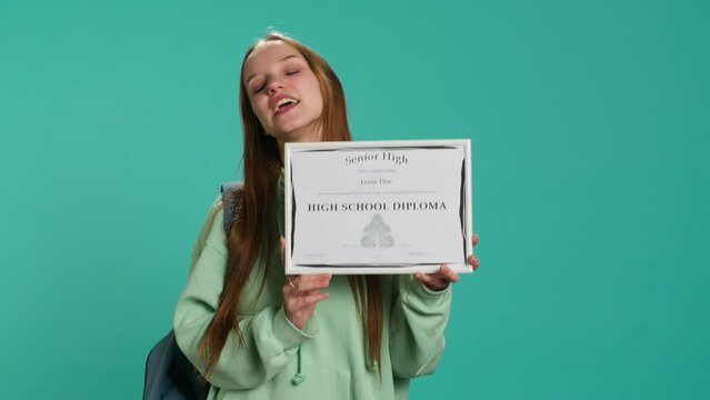 Cheerful teenager holding school award, excited after receiving accreditation for passing classes. Jolly person grateful for received honor, isolated over studio background, camera A