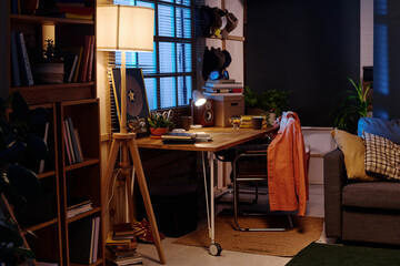 No people shot of part of living room room interior with wooden table, chair, bookcase and floor lamp in evening, copy space