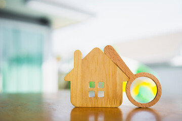 Hand holding magnifying glass and looking at house model, house selection, real estate concept.	