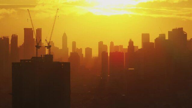 Aerial view of Manila at sunrise, showcasing the city's vibrant urban landscape with skyscrapers and construction sites bathed in golden light