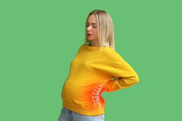 Pregnant woman feeling pain in spine on green background